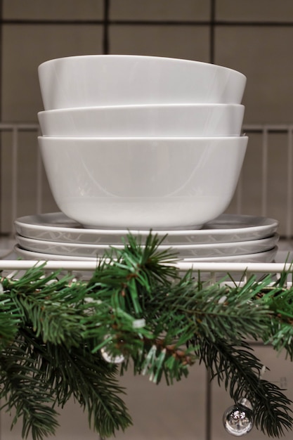 Christmas composition with stack of bowls and decorated fir tree