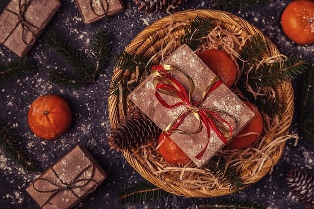 Christmas composition with tangerines, gift boxes, cones on dark  background.