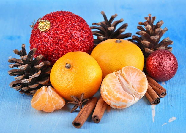 Christmas composition with tangerines on wooden table on blue surface