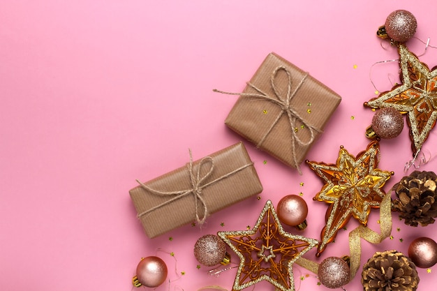 Christmas composition with toys, gifts, stars, balls and tinsel on a pink background. Flat lay, top view.