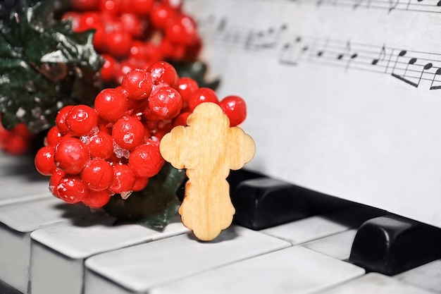 Christmas composition with wooden cross on piano, closeup