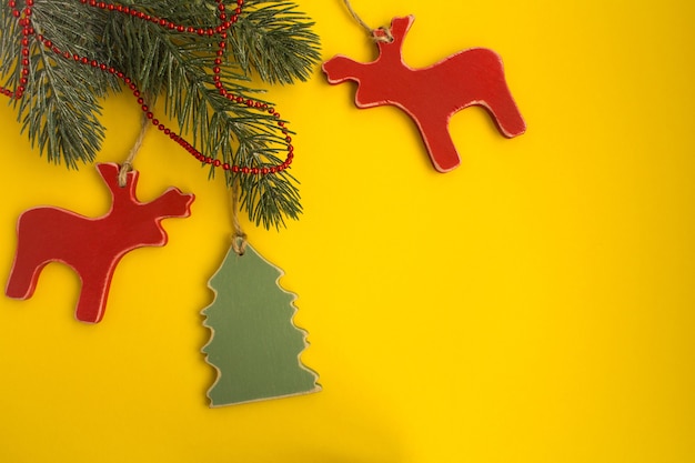黄色の背景に木のおもちゃでクリスマスの構成。上面図。コピースペース。
