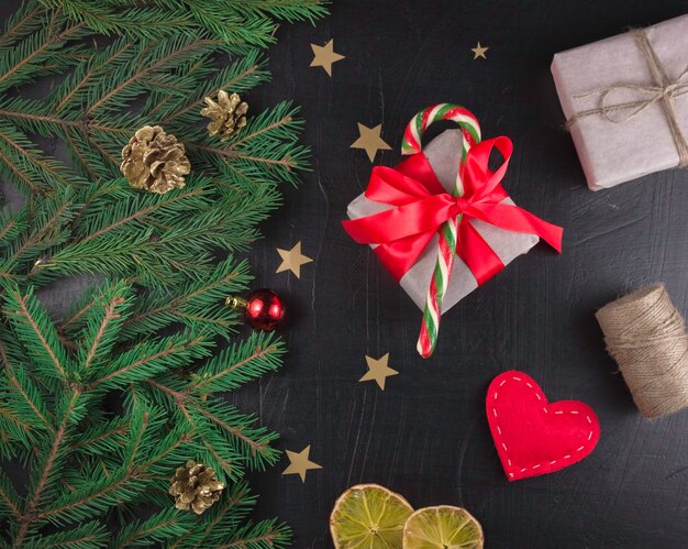 Christmas composition. Xmas cones, Christmas tree branches, gifts, festive decoration on black background. Flat lay, top view, with copy space.