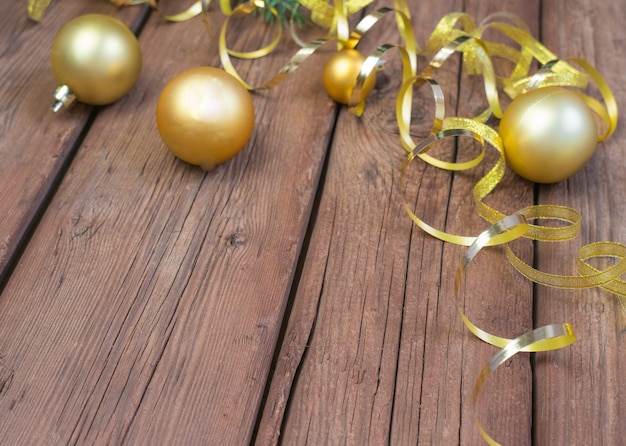 Christmas composition of yellow Christmas balls fir branches and a gold ribbon on a brown wooden