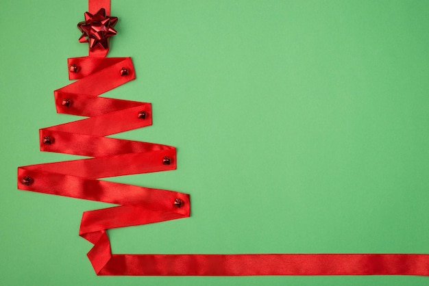 写真 クリスマスのコンセプト。背景の上に分離された装飾と弓で絹のようなリボンで作られた美しい明るいファンキーな色の木のクローズアップ写真