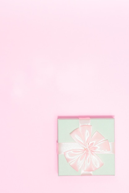 写真 クリスマス コンセプト グリーン パステル ギフト ボックスは、ピンクの背景に分離されたピンクのサテン リボンをラップします。