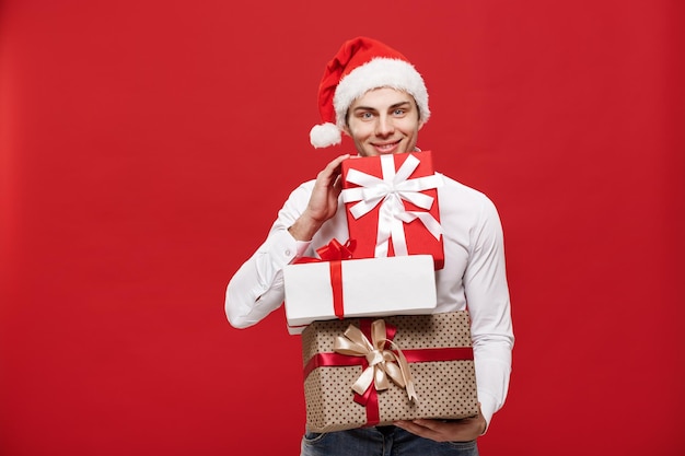 Concetto di natale bell'uomo d'affari caucasico felice con molti regali con cappello da babbo natale indossato in posa su sfondo bianco isolato