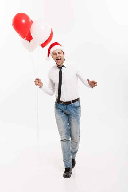 Christmas Concept Handsome happy Business man walking with red balloon celebrate merry christmas and happy new year wear santa hat