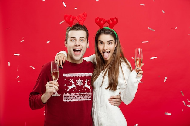 クリスマスのコンセプトクリスマスを祝うシャンパンフルートでクリスマスの乾杯を祝うトナカイの帽子をかぶった幸せな白人男性と女性