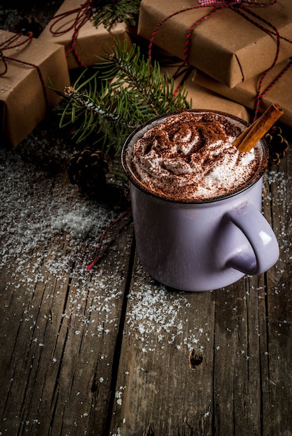 Рождественский концепт, горячий шоколад или какао со взбитыми сливками и специями, рождественские подарки, леденцы, ветка елки и сосновые шишки