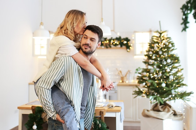 Christmas concept, man and woman in love having fun and kissing in decorated kitchen at home