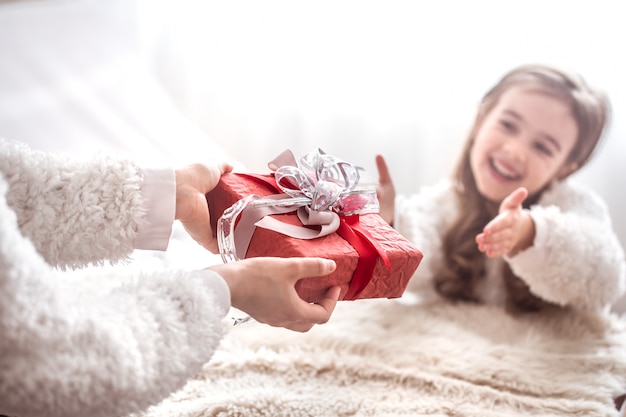 Christmas concept, Mom gives a gift to a little cute daughter, a place to text on a light wall