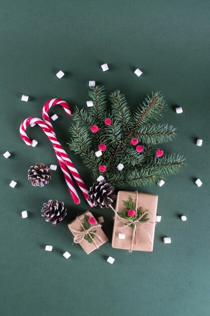クリスマスコンセプトビンテージベージュクラフトペーパーと自然な装飾のパッキングギフト。モミと赤いベリーの枝。トップビューフラットレイアウト