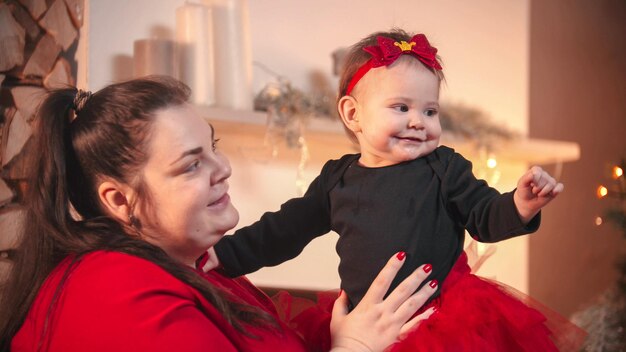 クリスマスのコンセプト彼女の小さな赤ん坊の娘を保持しているふっくらとした笑顔の女性