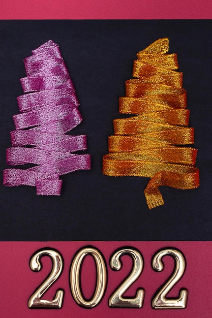 Christmas concept. Purple and gold Christmas tree made of ribbons and gold numbers on a colored background. Vertical photo. Template for postcards, packaging, advertising.