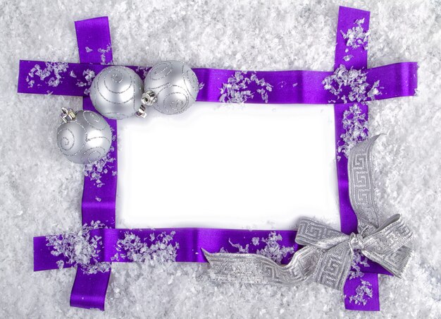 Concetto di natale pronto per la modifica. nastro viola nella neve con palline d'argento e nastro d'argento.