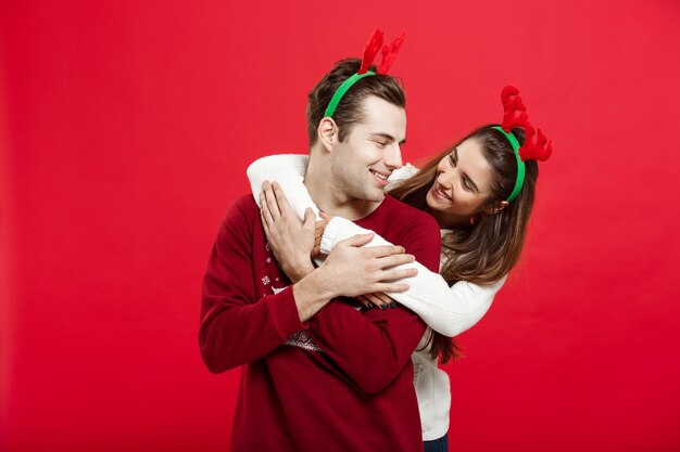 クリスマスコンセプトクリスマスセーターを着たロマンチックなカップルがお互いを抱きしめます