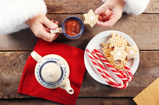 Christmas concept. Santa have a meal. Tasty cookies and cup of coffee on wooden background, close up