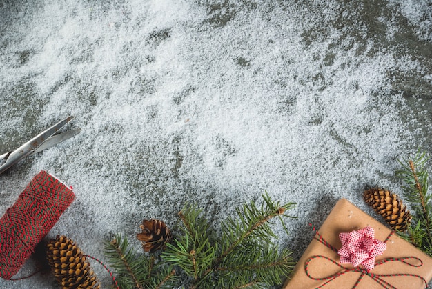 クリスマスのコンセプト、雪、クリスマスツリーの枝、ギフトやプレゼント、松ぼっくりや装飾とテーブルの背景