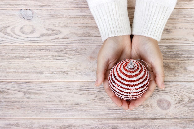 Christmas concept with hand and white ball - christmas tree toy. White round christmas ball in female hand.