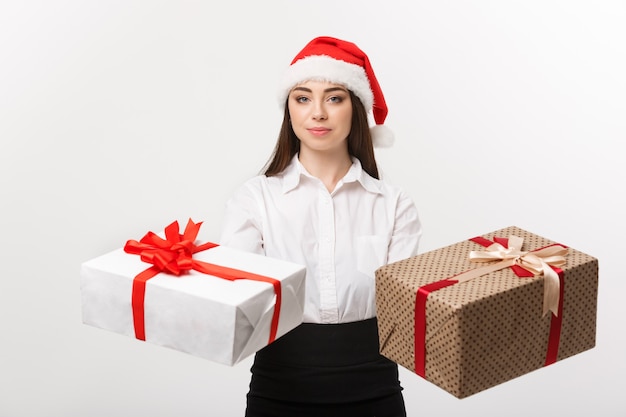 Christmas concept  young happy caucasian business woman with santa hat giving a choice of gift boxes  with copy space on side