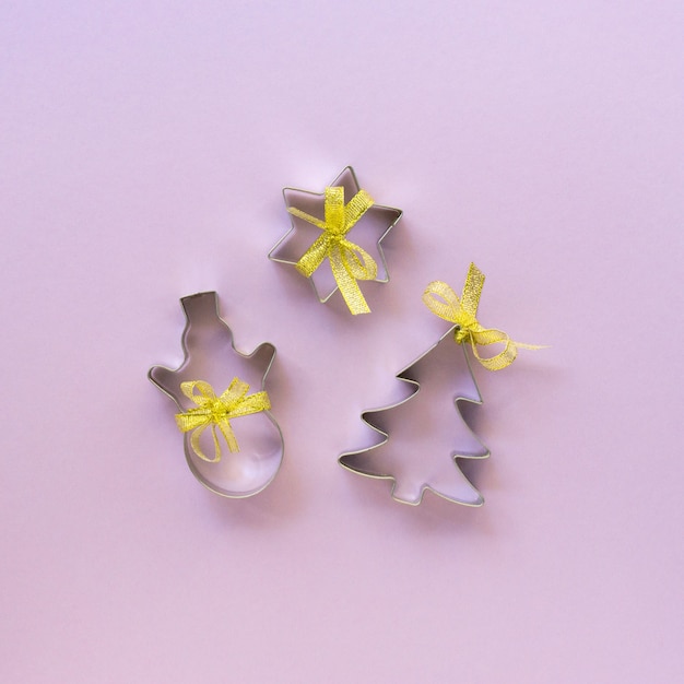 Christmas cookie cutters on a lilac background, top view.