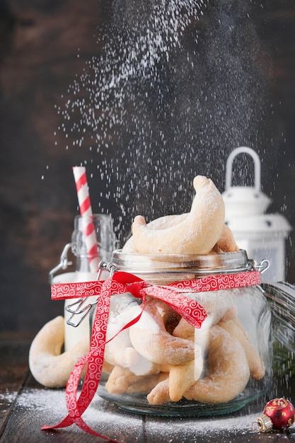クリスマス クッキーの三日月形 自家製の伝統的なクリスマス クッキー ショートブレッドの三日月形の瓶に古い木製の背景に粉砂糖を振りかけたドイツとオーストリアのクリスマスの伝統的なクッキー
