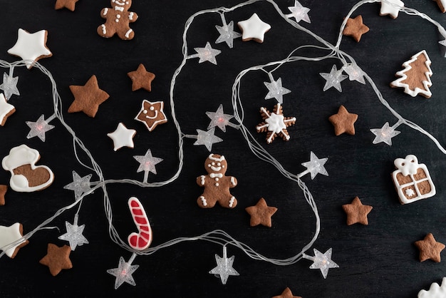 크리스마스 쿠키는 설탕 아이싱과 갈랜드를 검정색 배경에 윤기나게 했습니다.