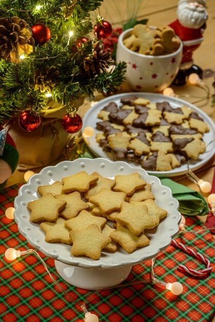 白い木製の背景にクリスマスのクッキーとライト