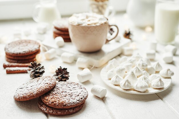 Christmas cookies and marshmallows on a white by the window