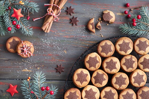 Christmas cookies with chocolate star on cooling rack with spices and decorated fir twigs