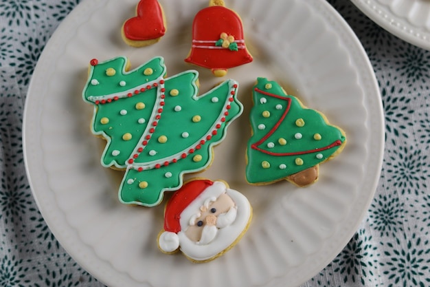 Christmas cookies with Christmas tree shape served in white plate with white background.