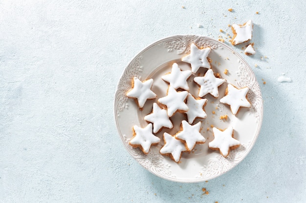 Biscotti di natale con glassa su piatto bianco su azzurro.