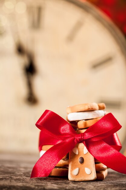 Christmas cookies with red bow against old clock