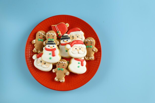 빨간 접시에 산타클로스, 눈사람, 생강 남자 모양이 있는 크리스마스 쿠키가 제공됩니다.