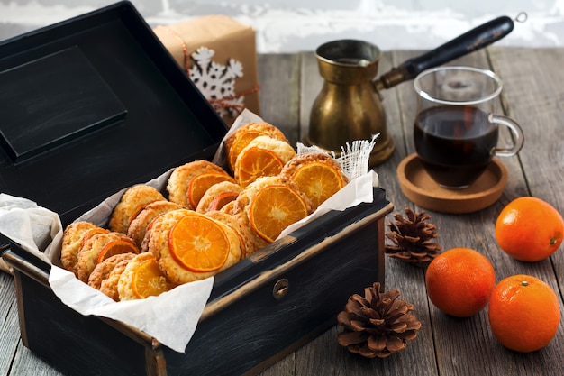 Christmas cookies with sliced tangerines and Christmas toys in a dark box. Selective focus.