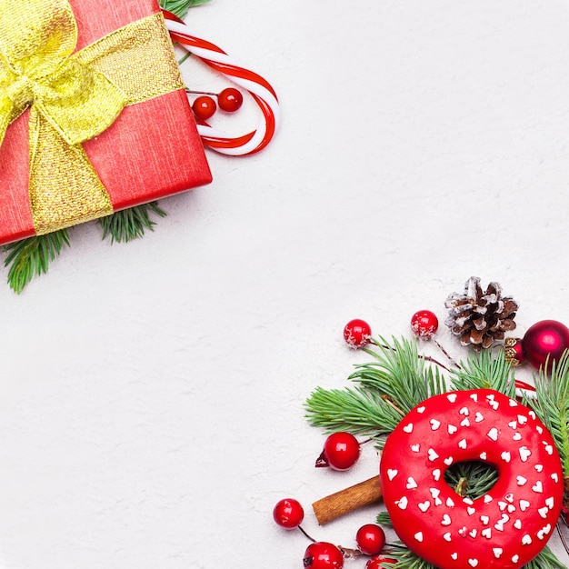 Christmas corner composition with green Xmas fir branch red holly berries and baubles on white background