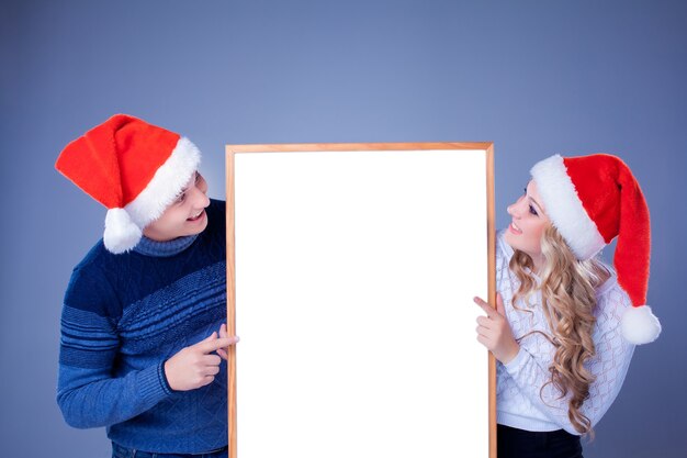 Рождественская пара держит белую доску с пустой копией пространства