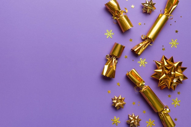 Christmas crackers with shiny confetti on color background top view copy space