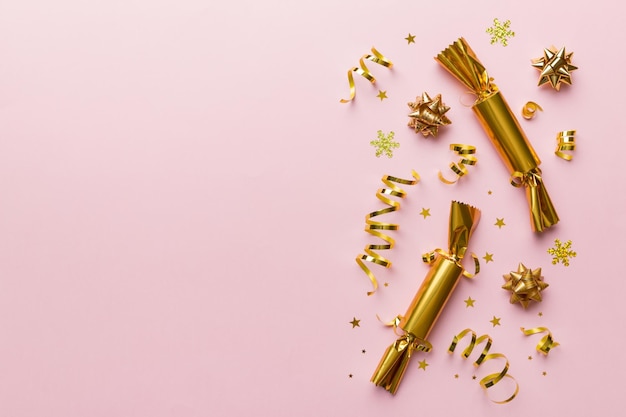 Christmas crackers with shiny confetti on color background top view copy space