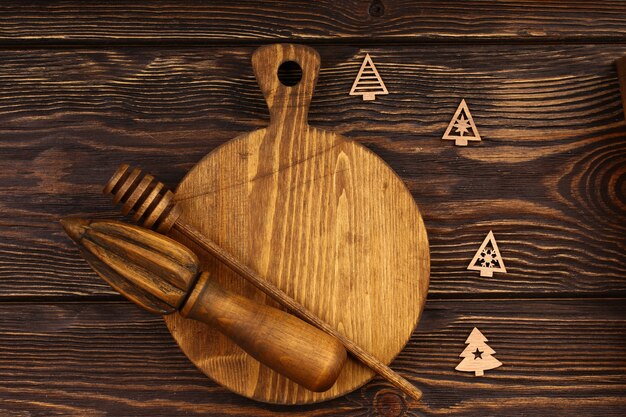 Рождественский кулинарный план на деревянном фоне. Деревянная разделочная доска с рождественскими предметами для меню праздничного стола. Вид сверху, плоский стиль.