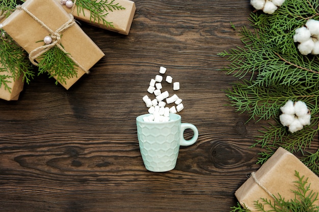 Christmas cup, marshmallow and gift boxes on dark wooden board, top view