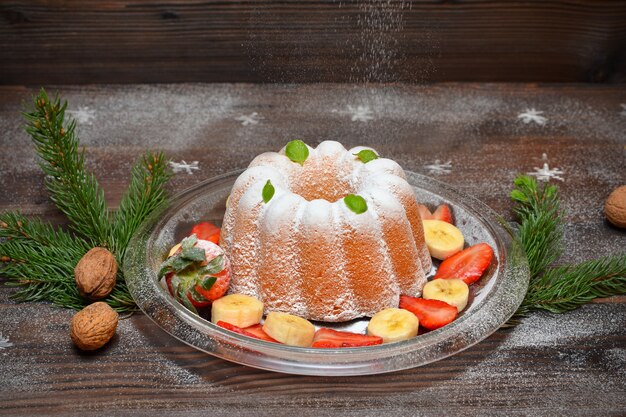 Christmas cupcake with fruit and powdered sugar on the festive table