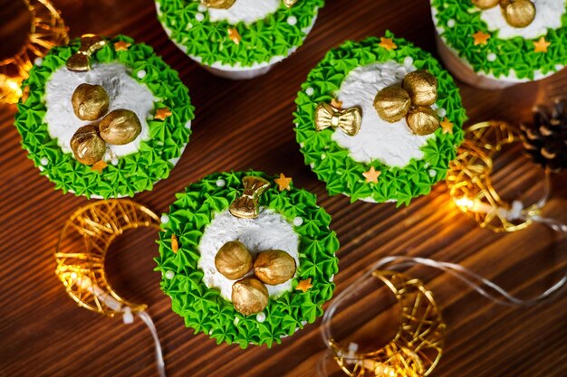 光る花輪の背景にヘーゼル ナッツのクリスマス カップケーキ
