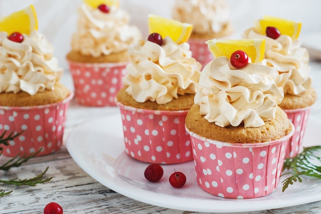 Christmas cupcakes with whipped cream topping and cranberries,orange. festive food dessert.