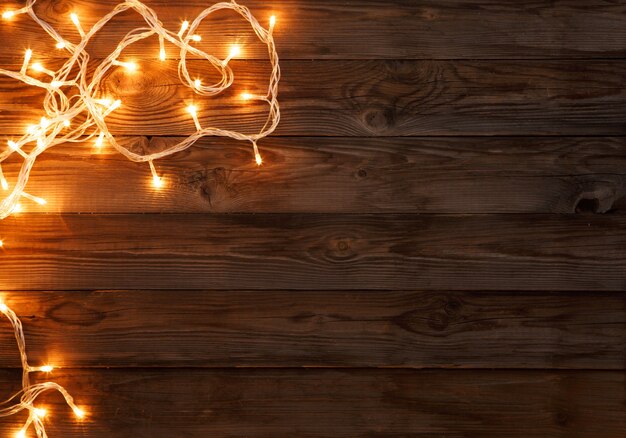 Fondo di legno marrone scuro di natale decorato con luci brillanti
