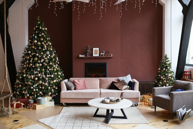 Christmas dark interior of cozy home with christmas tree fireplace sofa and armchair