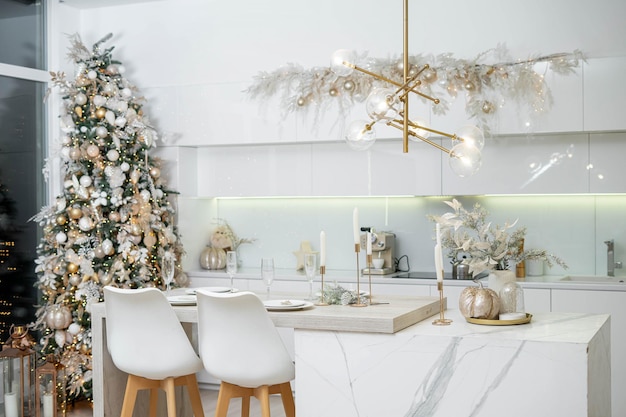 Christmas decor. Bright interior of white kitchen with decorated Christmas tree, garlands