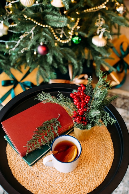 Decorazioni natalizie e una tazza di tè con ghirlande bokeh sull'albero di natale e divano di velluto verde