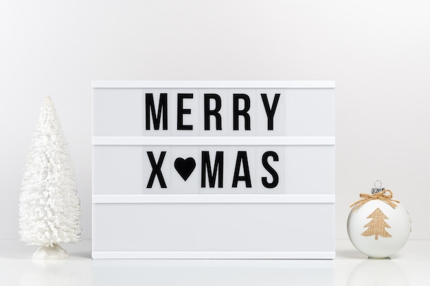 Decorazioni natalizie e lightbox con testo merry xmas sul tavolo bianco